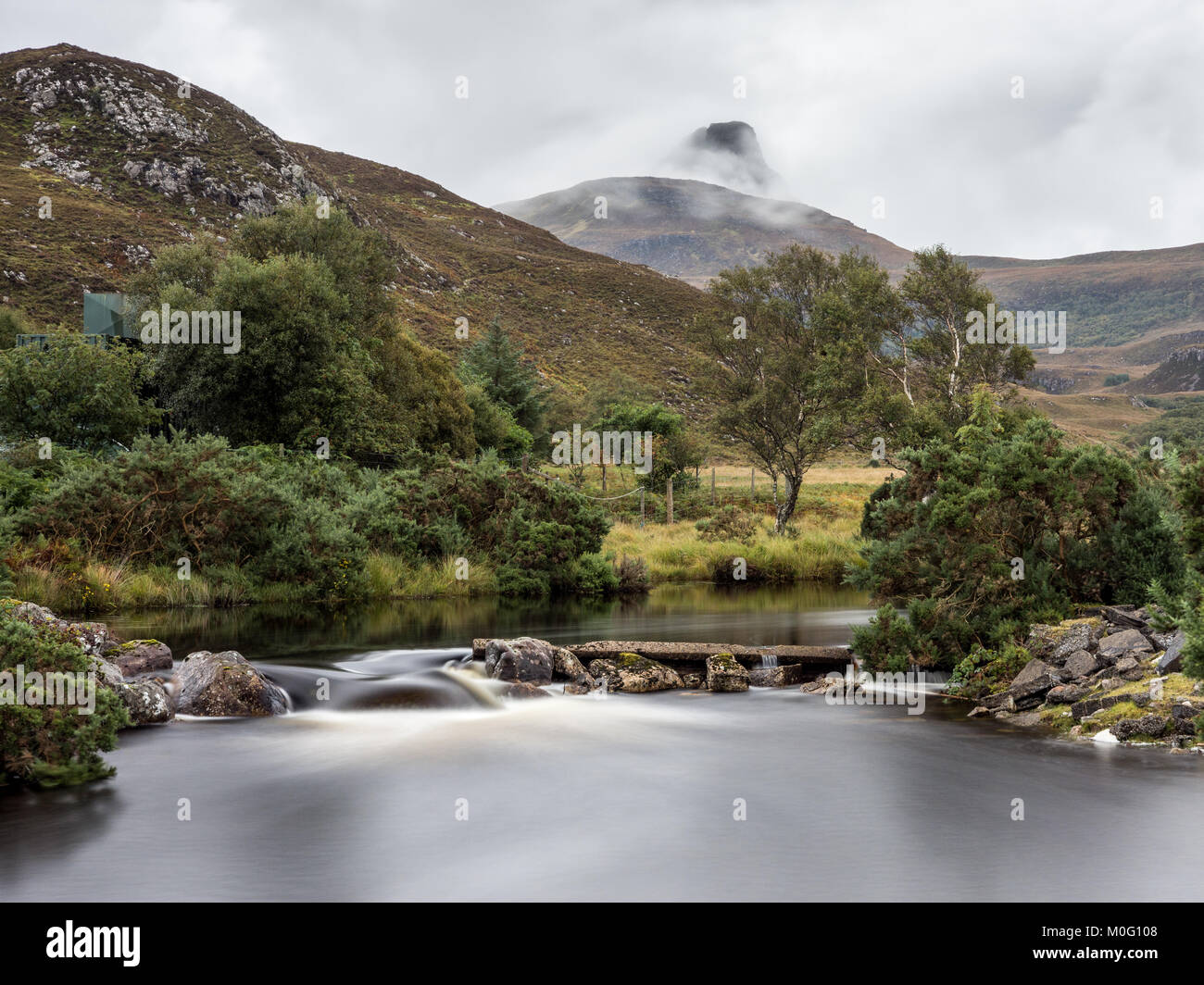 La montagna Stac Pollaidh sorge in nuvole dietro il fiume Polly in Assynt distretto di nord-ovest Highlands della Scozia. Foto Stock
