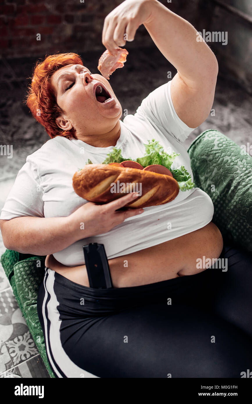 Donna sovrappeso mangia sandwich, bulimic, obesità problema. Uno stile di vita poco salutare, femmina di grasso Foto Stock