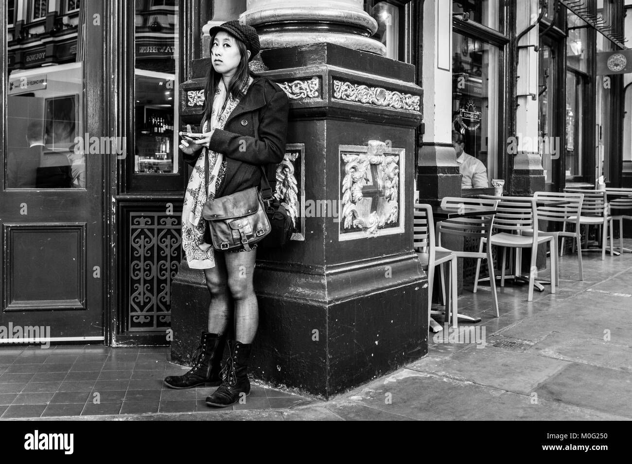 Fotografia di strada in bianco e nero a Londra: Giovane donna al telefono cellulare a Leadenhall Market, City of London. Foto Stock