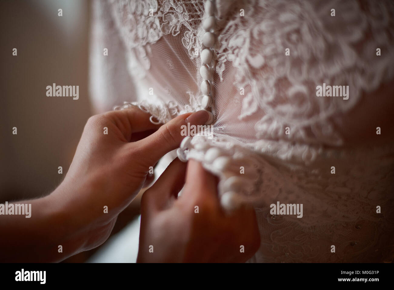 Close up damigella aiutando la sposa di vestire prima della cerimonia Foto Stock