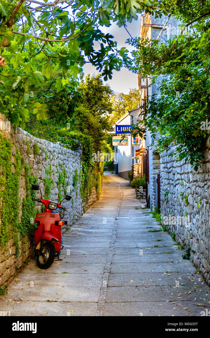 Moto scooter su strada tranquilla in Osor, sull'isola croata di Cres. La Croazia. Maggio 2017. Foto Stock
