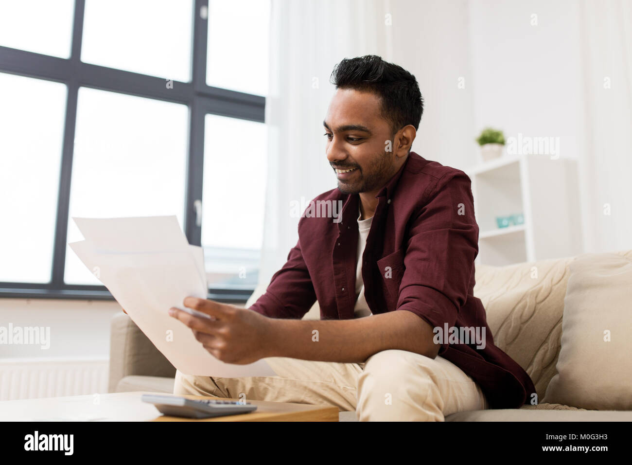 Uomo con documenti e calcolatrice a casa Foto Stock