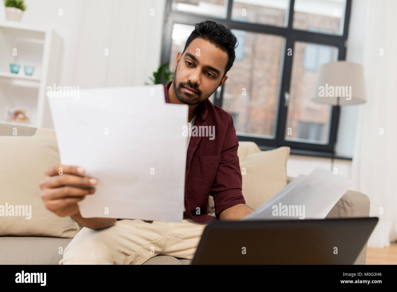 Turbare l uomo con il computer portatile e i documenti a casa Foto Stock