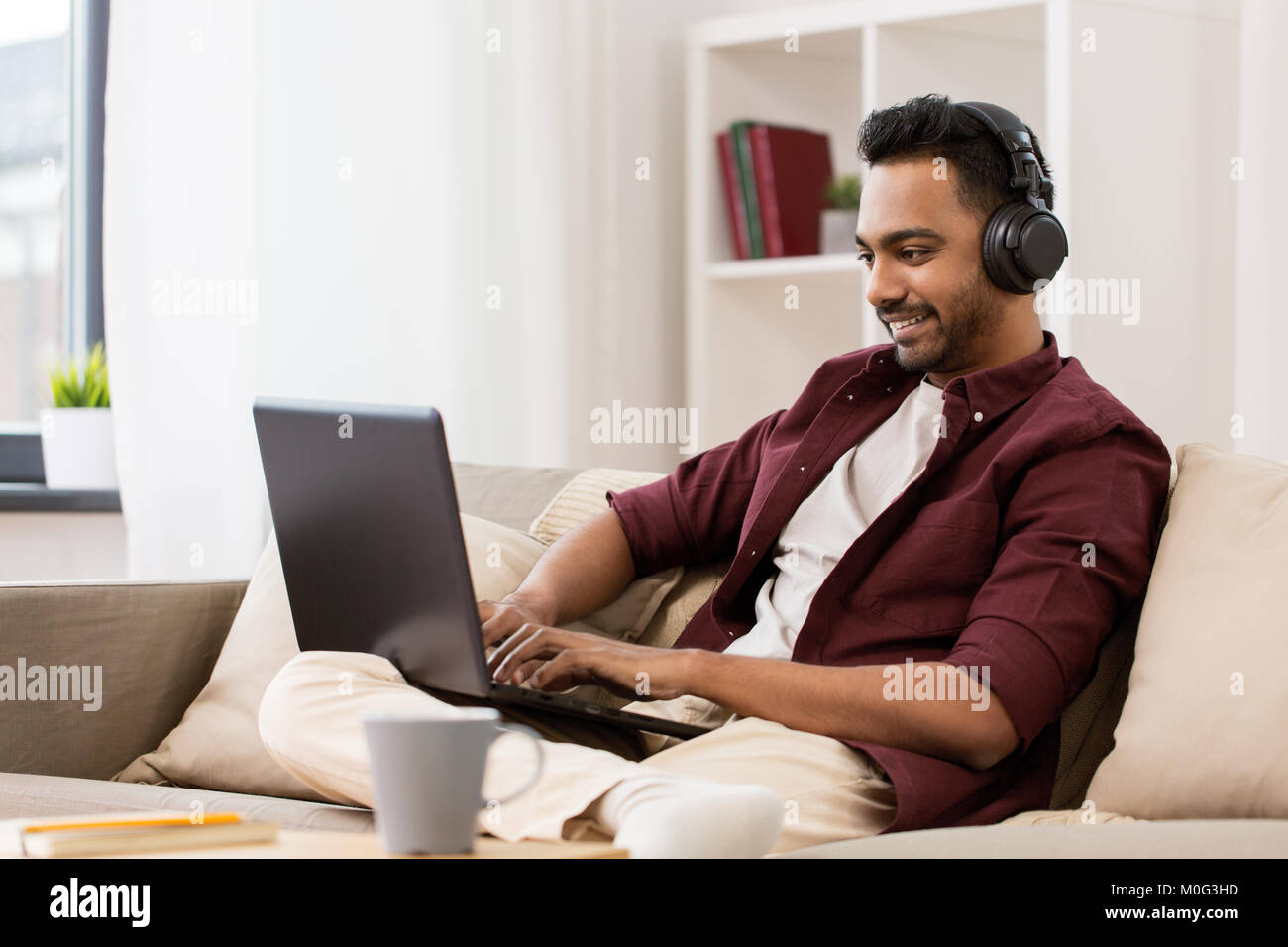 L'uomo nelle cuffie con il computer portatile per ascoltare musica Foto Stock