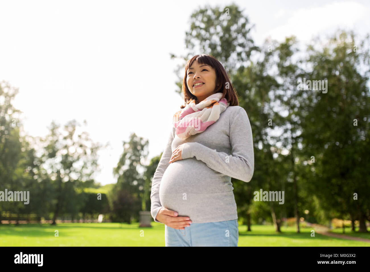 Felice incinta donna asiatica in posizione di parcheggio Foto Stock