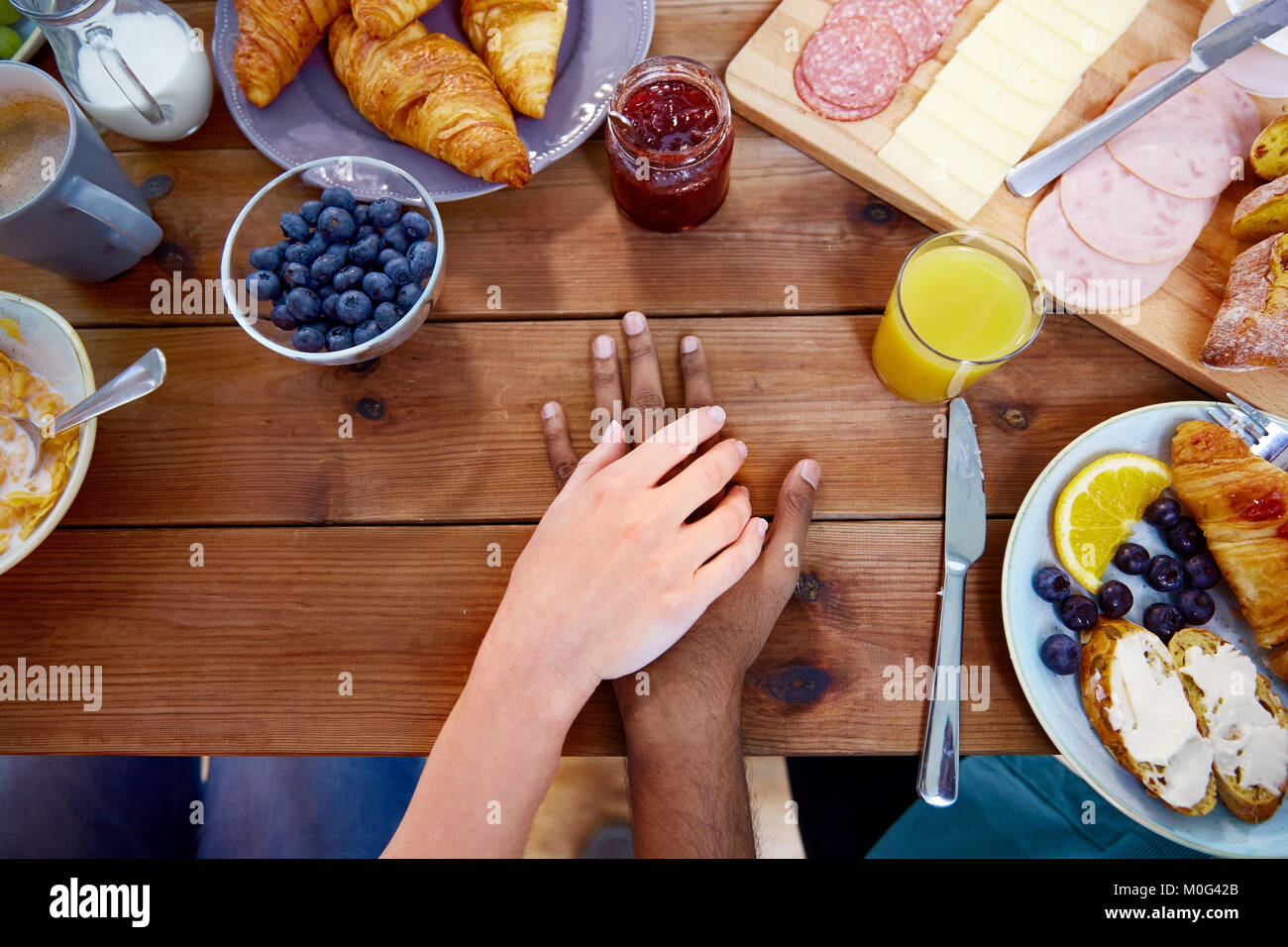 Accoppiare le mani sul tavolo pieno di cibo Foto Stock