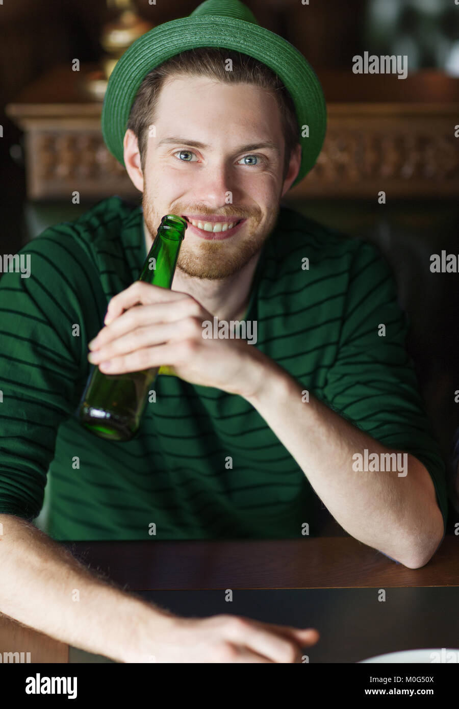 Uomo di bere birra dal verde bottiglia al bar o pub Foto Stock