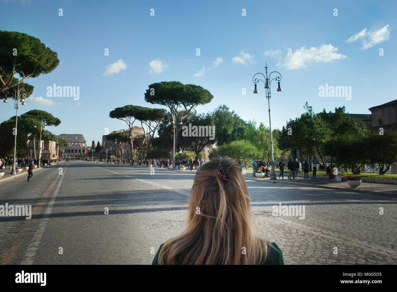 Foro romano, ragazza bionda che cammina verso il Colosseo. donna visitando la via dei Fori imperiali e Roma Foto Stock