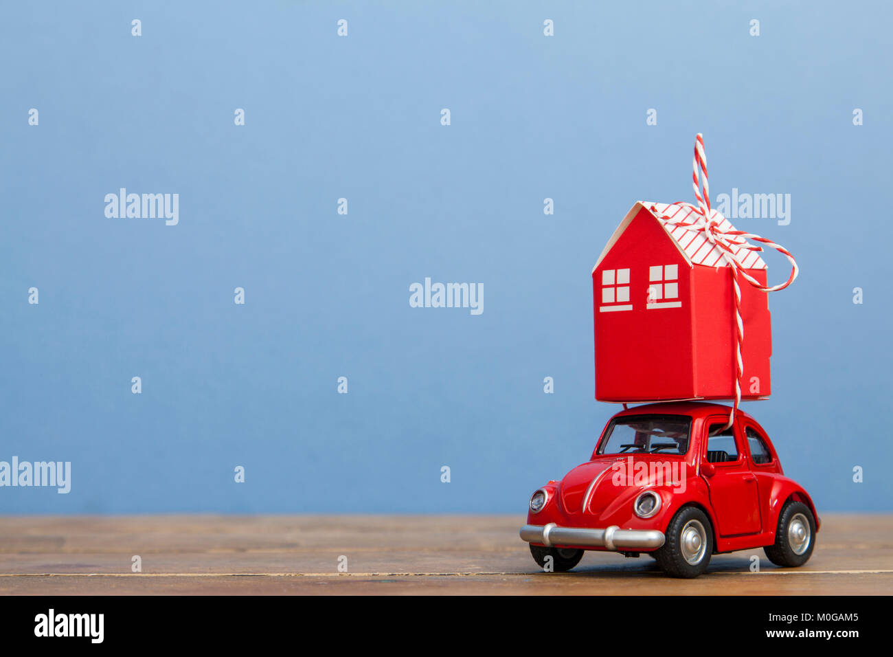 LONDON, Regno Unito - 19 gennaio 2018: un giocattolo auto oy portando una pila di case contro uno sfondo blu. Casa mobile concept Foto Stock