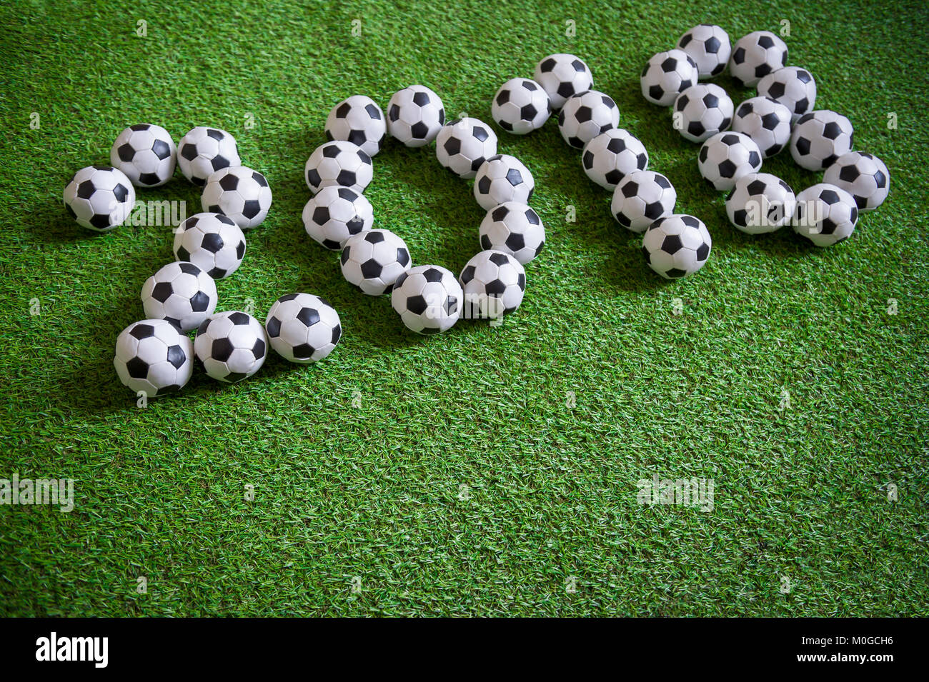 Sporty Anno Nuovo messaggio 2018 formata da palloni da calcio sul calcio verde sullo sfondo del passo Foto Stock