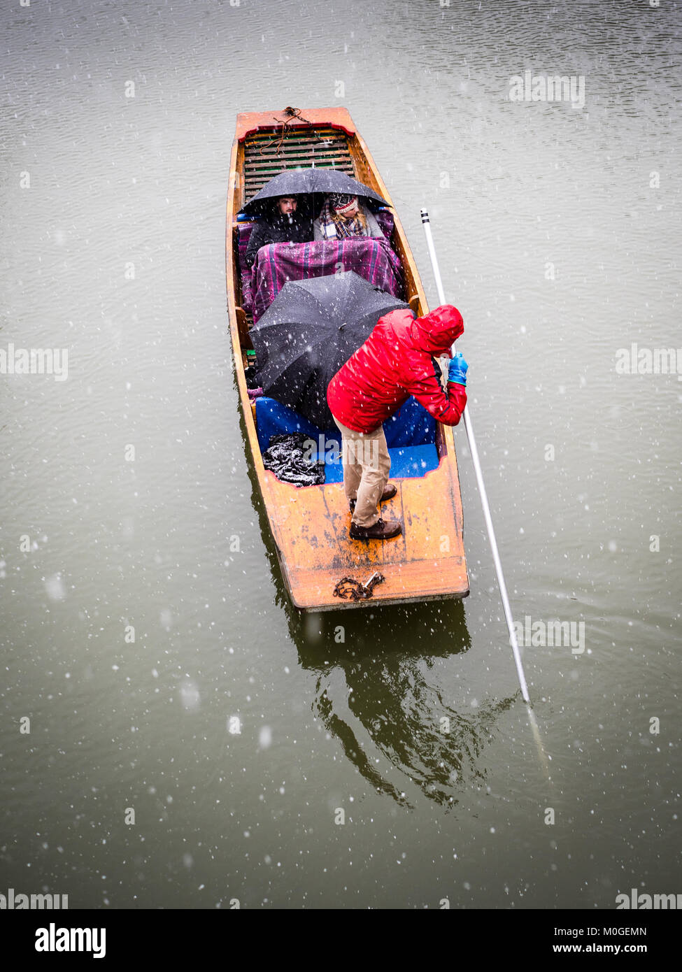 Inverno Punting - turisti huddle sotto le coperte e ombrelloni che prendono un punt lungo il fiume Cam in caso di neve. Foto Stock
