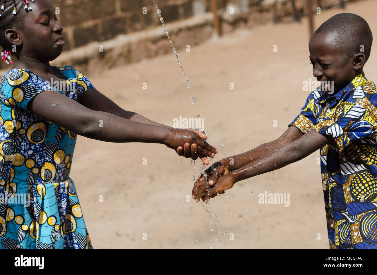 Due bambini africani la pulizia delle mani all aperto con acqua fresca Foto Stock