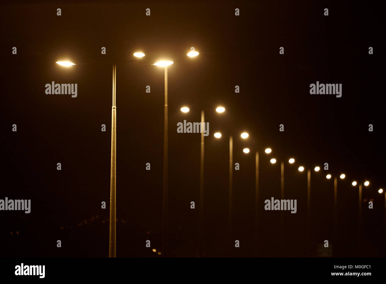 Alta colonna autostrada luci accese di notte nel Regno Unito Foto Stock