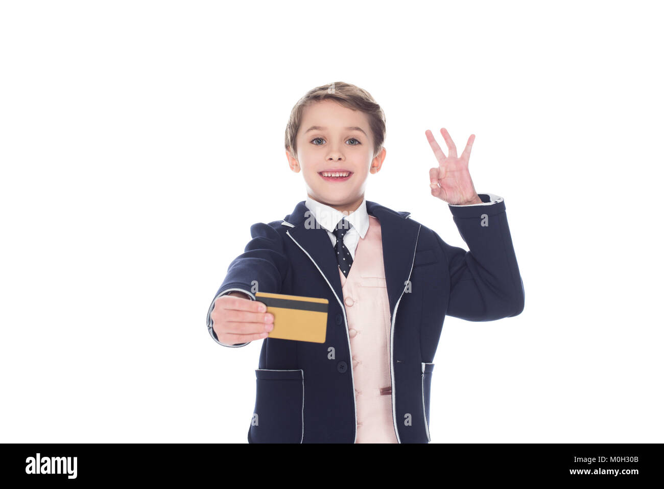 Little Boy holding golden carta di credito e segno ok, isolato su bianco Foto Stock