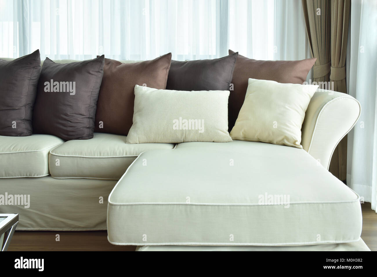 L forma divano beige con varia di colore marrone di cuscini Foto stock -  Alamy