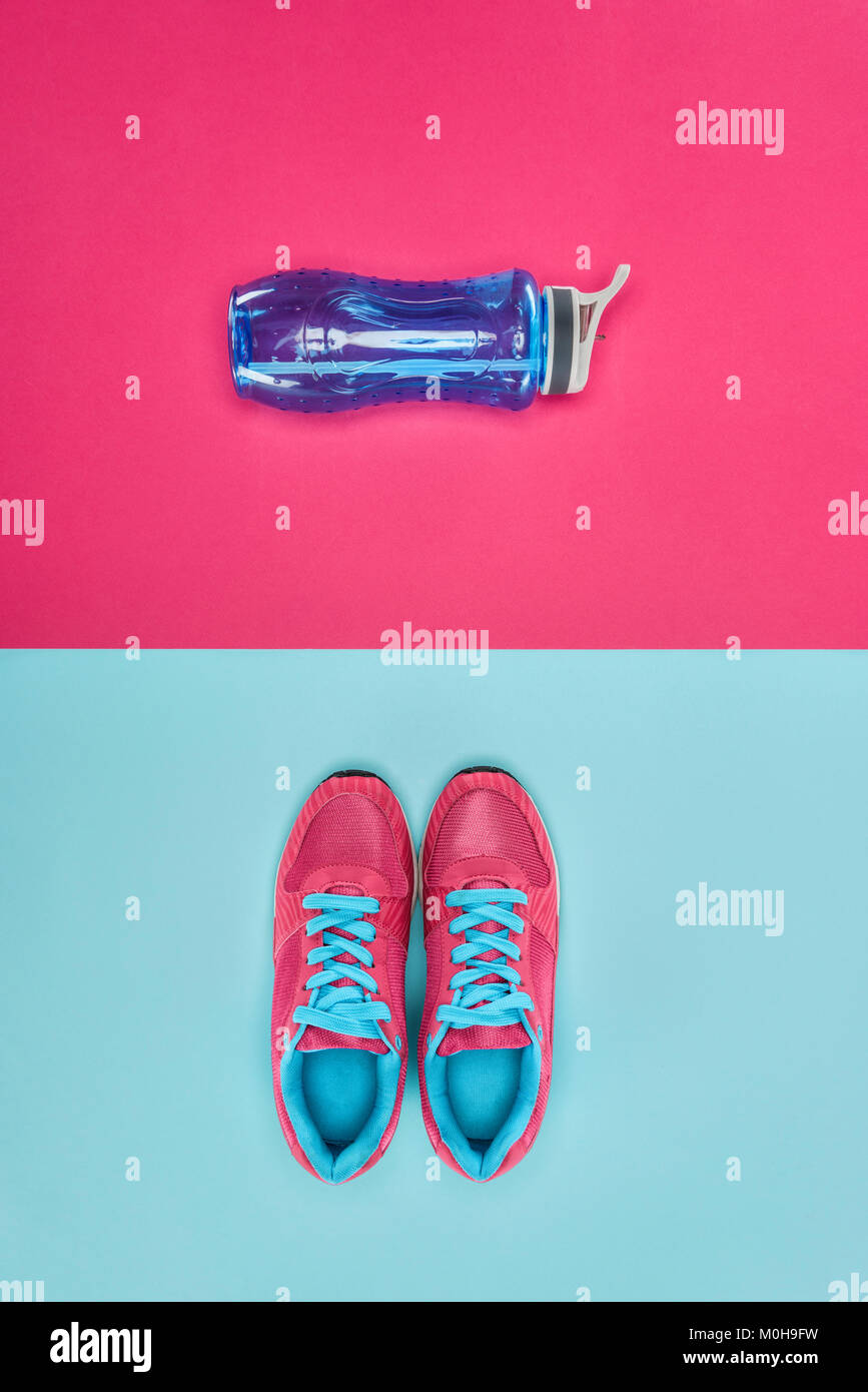 Attrezzature sportive con scarpe e una bottiglia d'acqua isolato in rosa e in blu Foto Stock