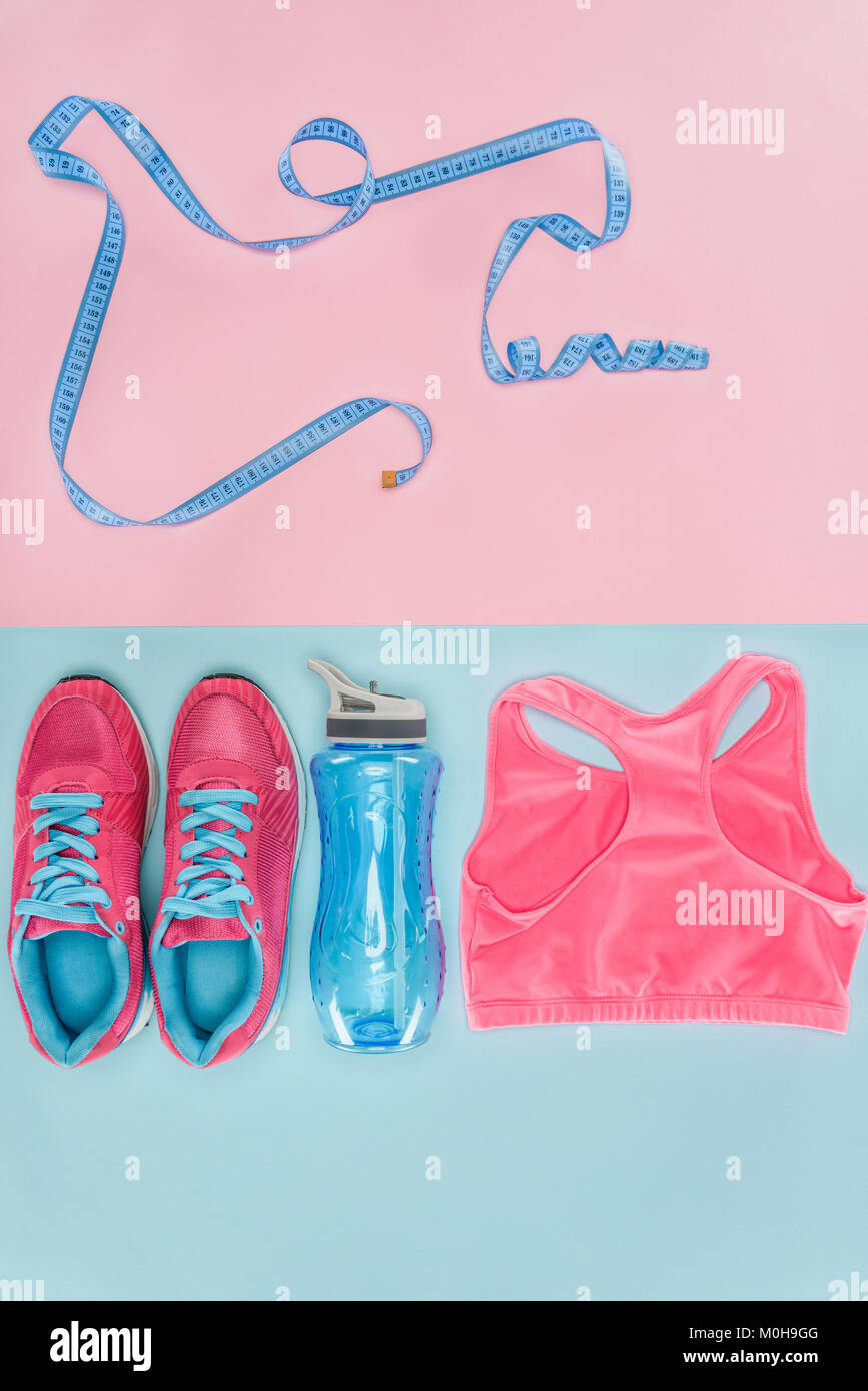 Attrezzature sportive con scarpe, nastro di misurazione e sport top isolato in rosa e in blu Foto Stock