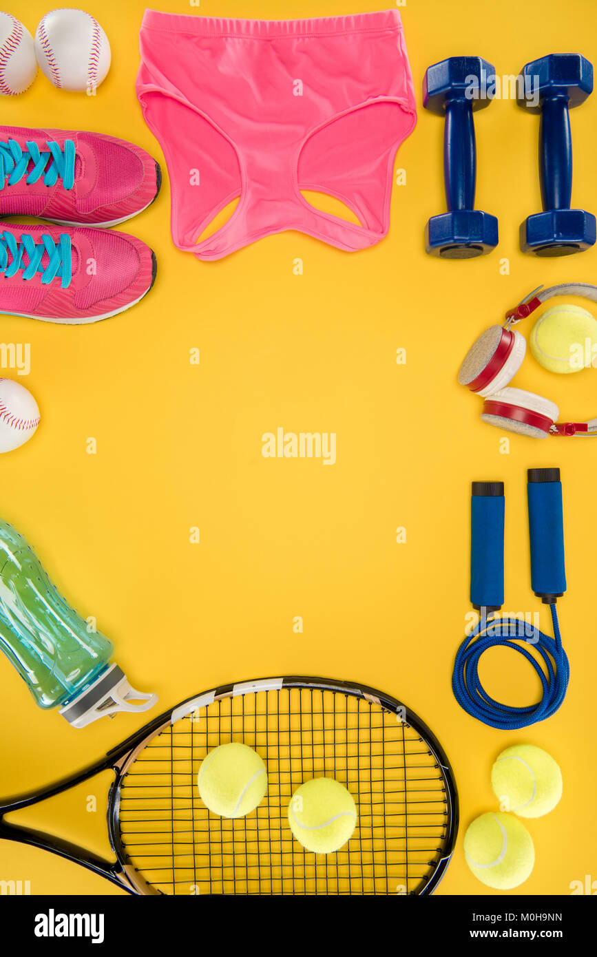 Attrezzature sportive con scarpe, manubri, sport top e cuffie isolato su giallo Foto Stock