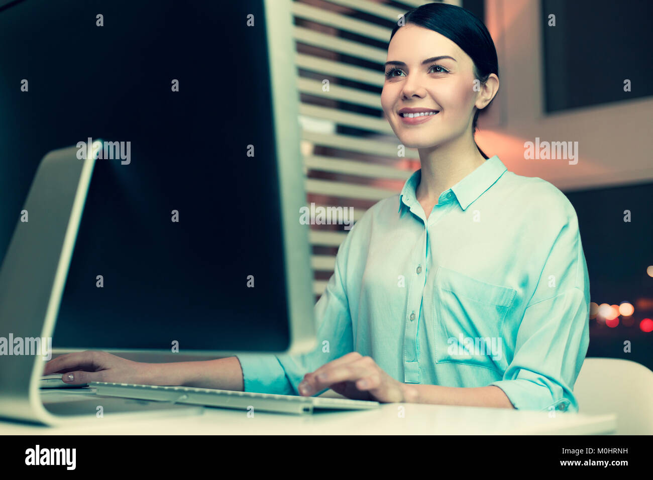 Piacevole donna sorridente digitando una relazione sul lavoro Foto Stock