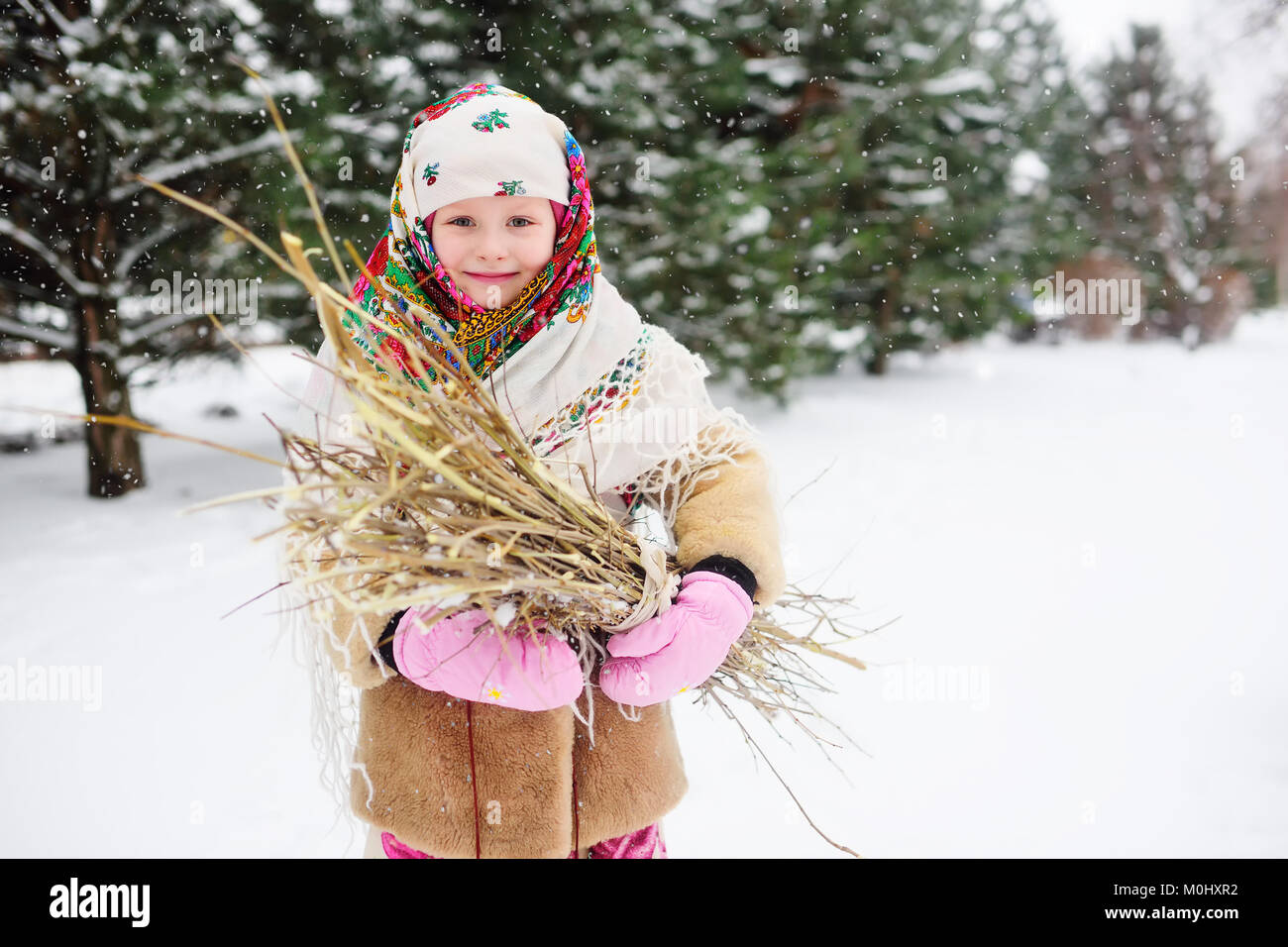 La ragazza del bambino in una pelliccia e in una sciarpa in stile russo con un mazzetto di sottobosco Foto Stock