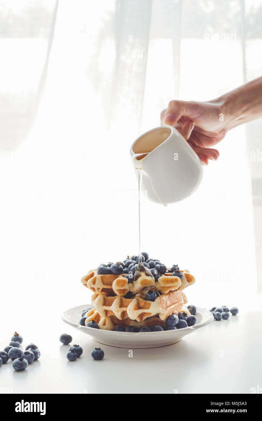 Ritagliato colpo di donna versando freschi e deliziosi del miele per gustose cialde Foto Stock