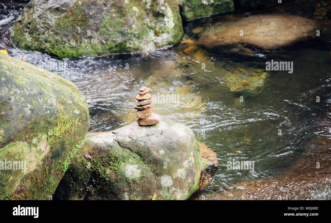Impilati peddles adiacente ad un flusso nella foresta che simboleggia lo zen e l'equilibrio, Penedo, Rio de Janeiro, Brasile Foto Stock