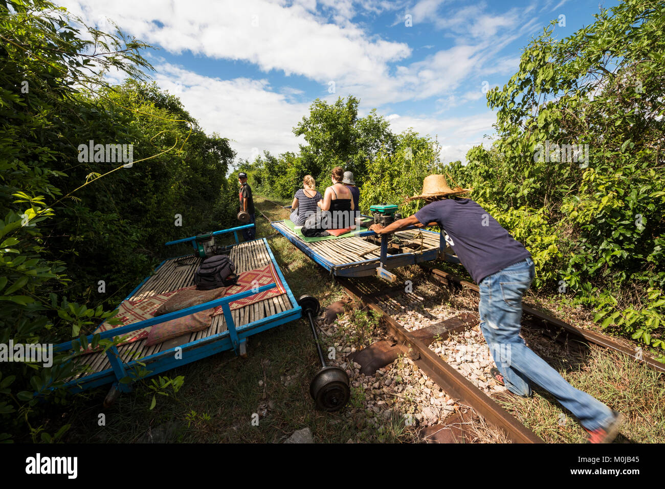 Gli uomini di spingere la piattaforma di bambù del Norry, bamboo treno; Battambang, Cambogia Foto Stock