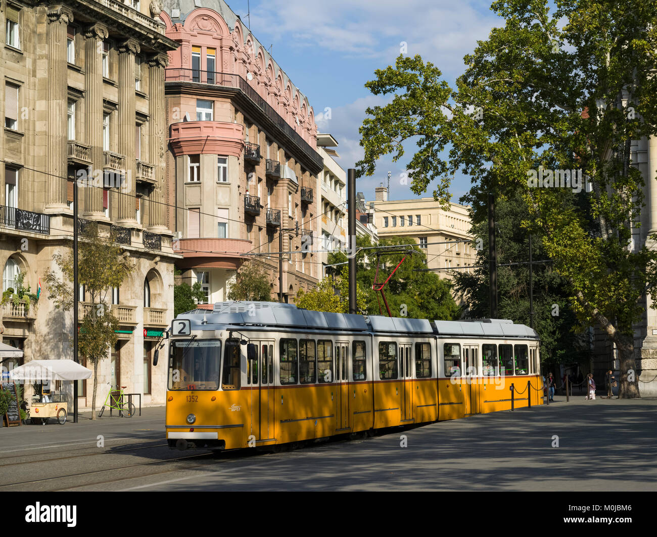 Un tram giallo scorre su di una pista per le strade; Budapest, Budapest, Ungheria Foto Stock