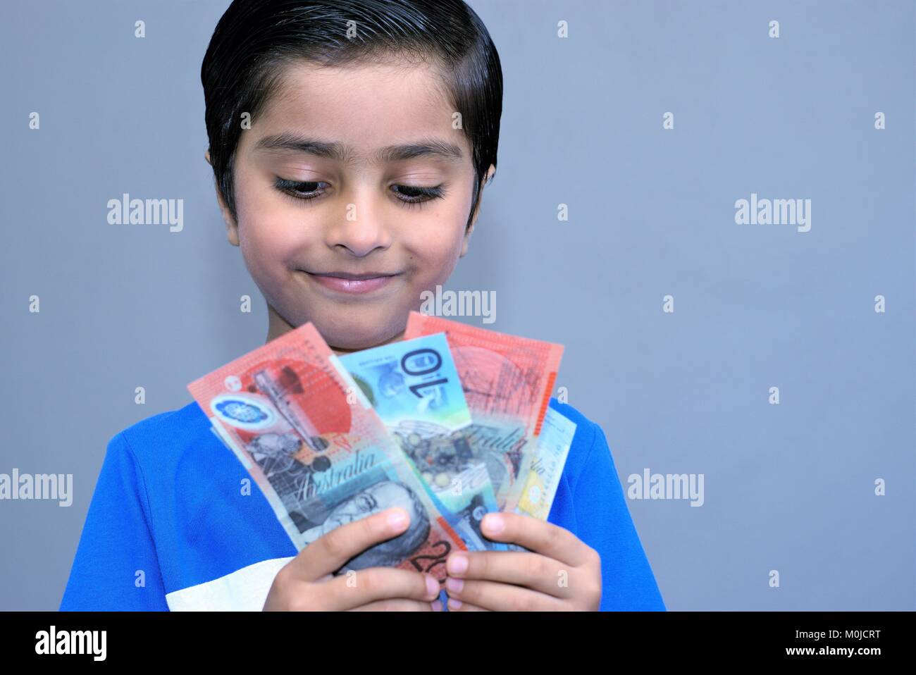 Allegro kid holding denaro. Dollari australiani in mani del bambino felice. Concetto di pocket money. Emozionato bambino con denaro. Foto Stock