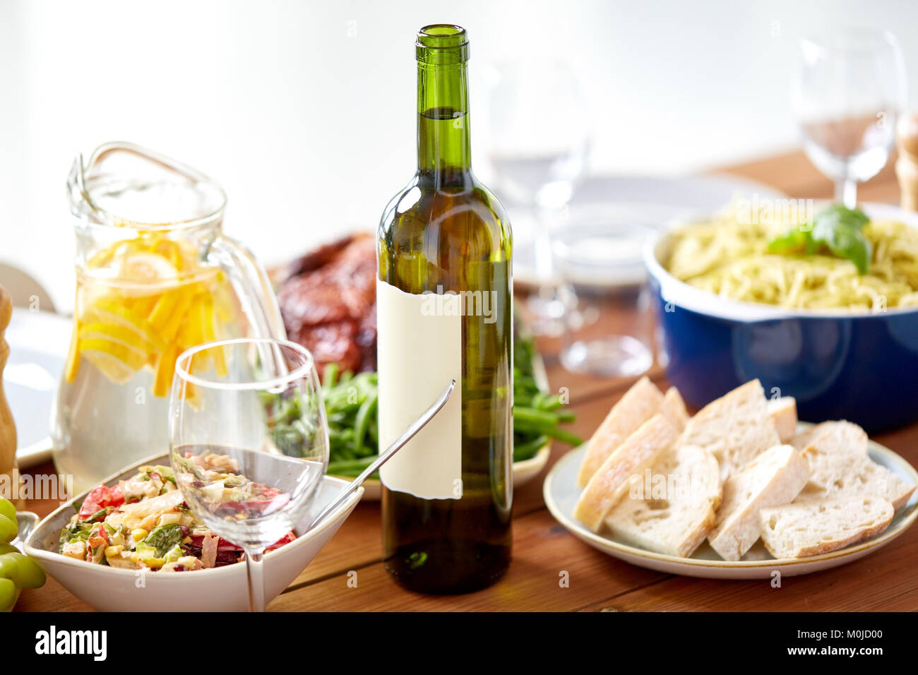 Bottiglia di vino e cibo servito su un tavolo di legno Foto Stock