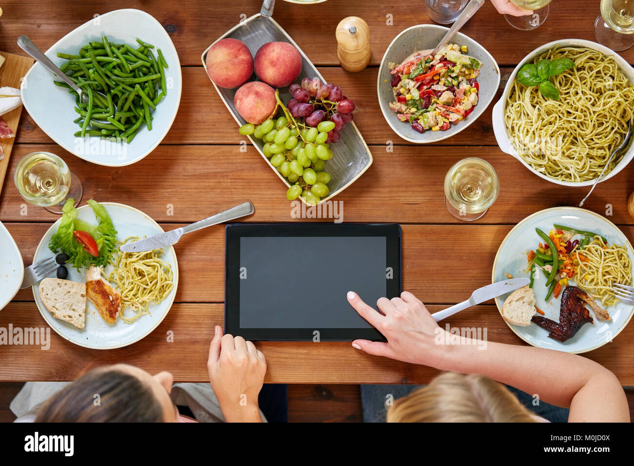 Le donne con tablet pc al tavolo pieno di cibo Foto Stock