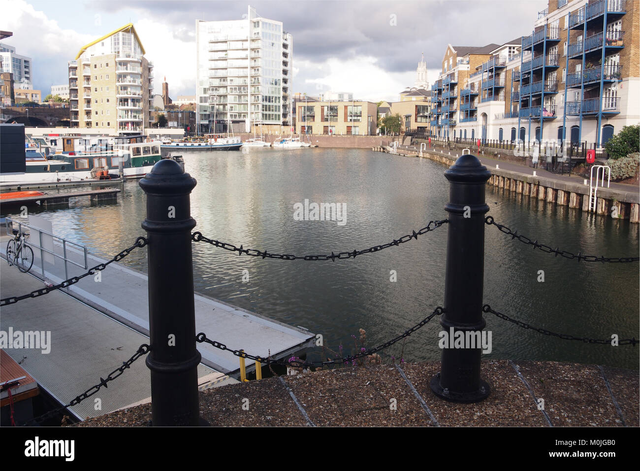 Una vista del bacino Limehouse,east London con pali di ferro e la maglia della catena delle barriere in primo piano e proprietà residenziali in background Foto Stock