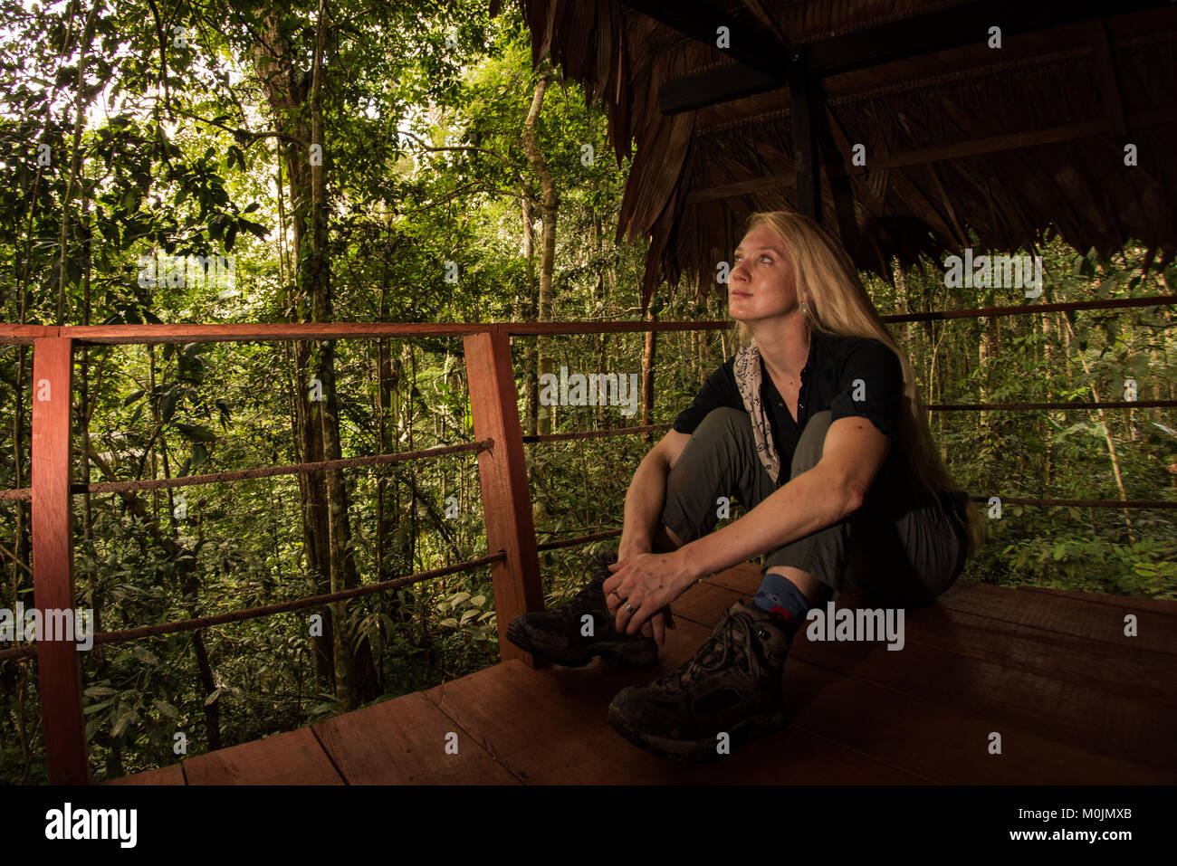 Una donna bionda si rilassa sul balcone di un ecolodge. Foto Stock
