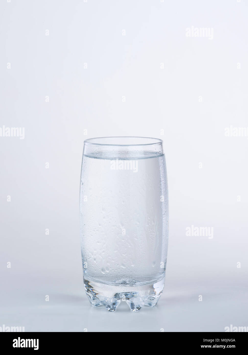 Bicchiere di acqua con condensati scende su sfondo bianco Foto Stock