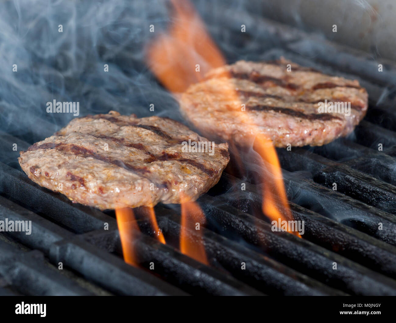 Due pezzetti di carne di pollo Burger bistecche alla griglia con fiamme. La cottura di pollo o grill barbecue barbecue o su carboni di legna. Close up Foto Stock