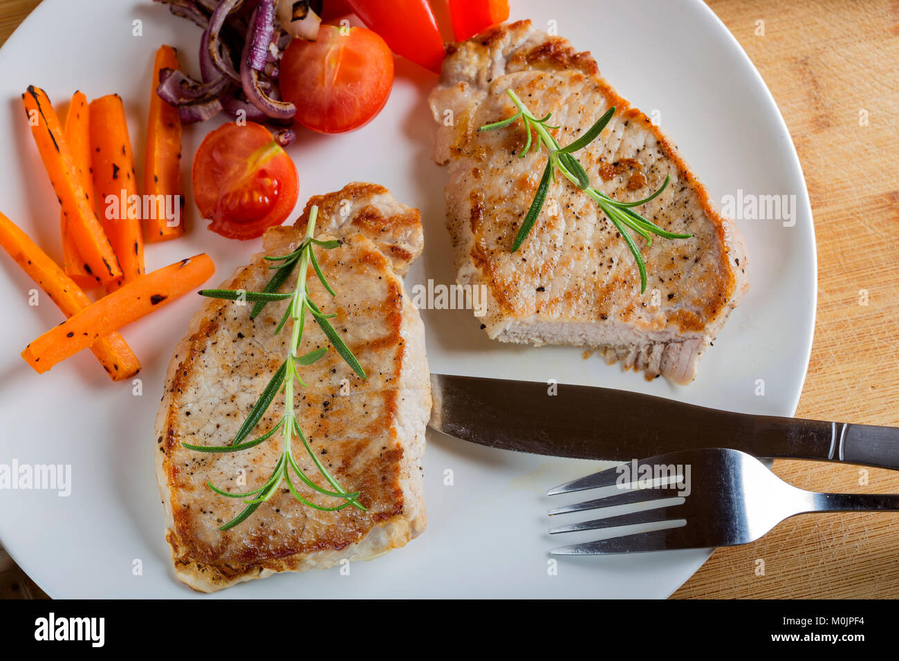 Pezzi fritto di tritare la carne di maiale con verdure alla griglia su una piastra di close-up vista da sopra. orizzontale Foto Stock