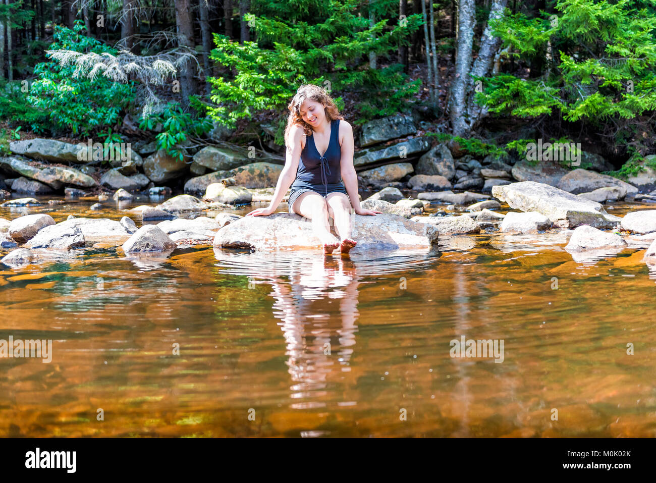 Felice giovane donna sorridente per godersi la natura in pace, calma Red Creek fiume in Dolly zolle, West Virginia durante la giornata soleggiata con riflessione piedi di immersione Foto Stock