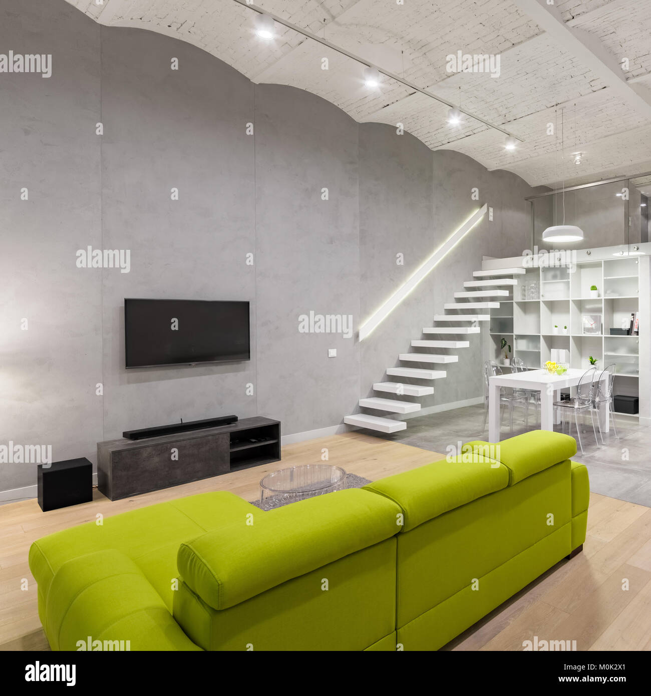 Home interno con grande, verde lettino, tv e soppalco Foto Stock