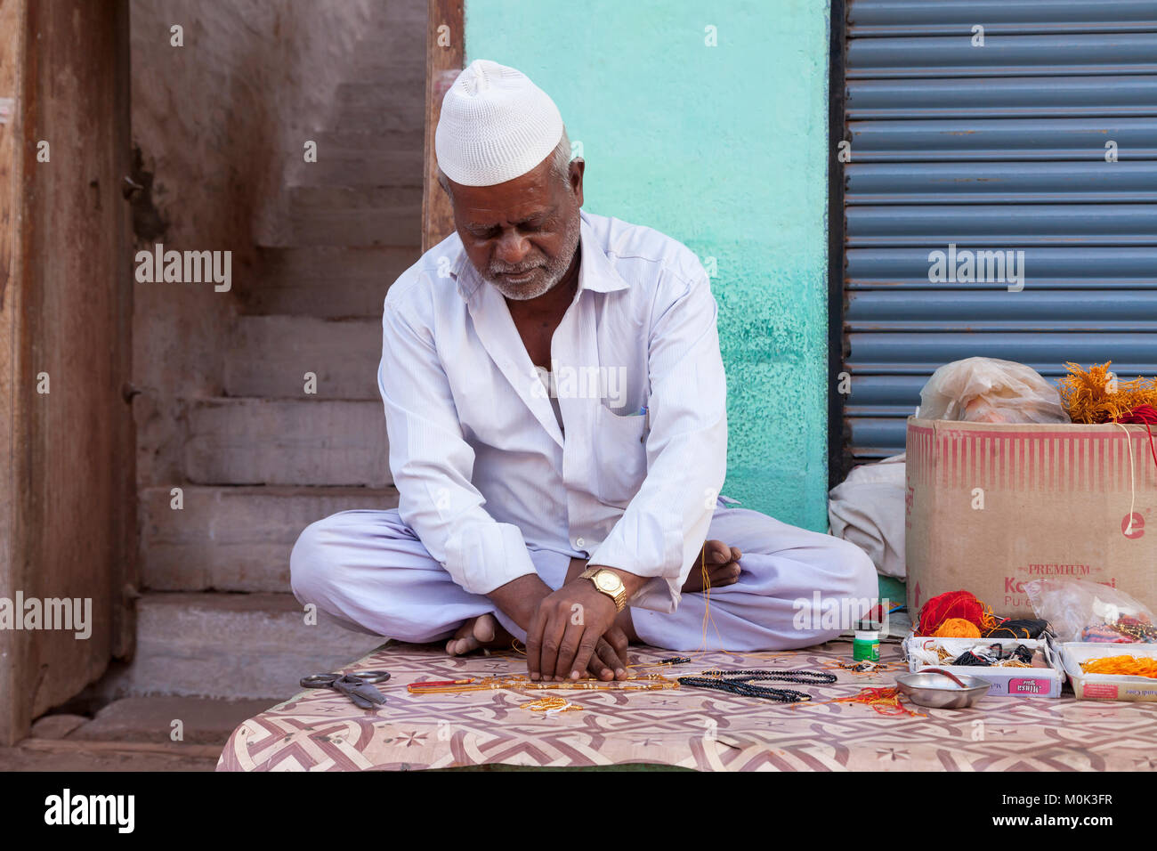 India, Karnataka, Badami, uomo sul filo di perle della catena Foto Stock