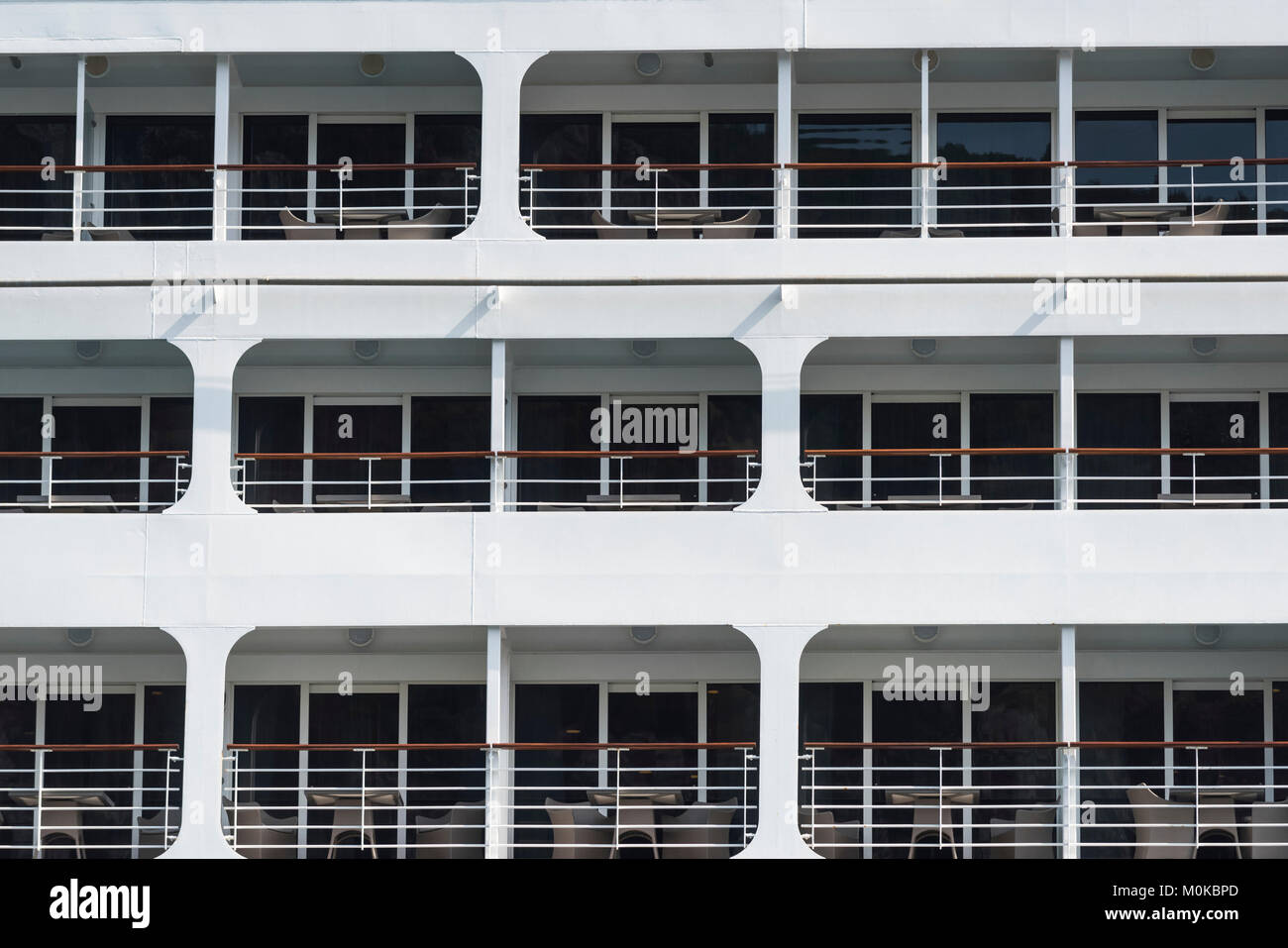 Tre livelli sul lato di una barca con sedie sui balconi e pareti di vetro; Kotor, Opstina Kotor, Montenegro Foto Stock