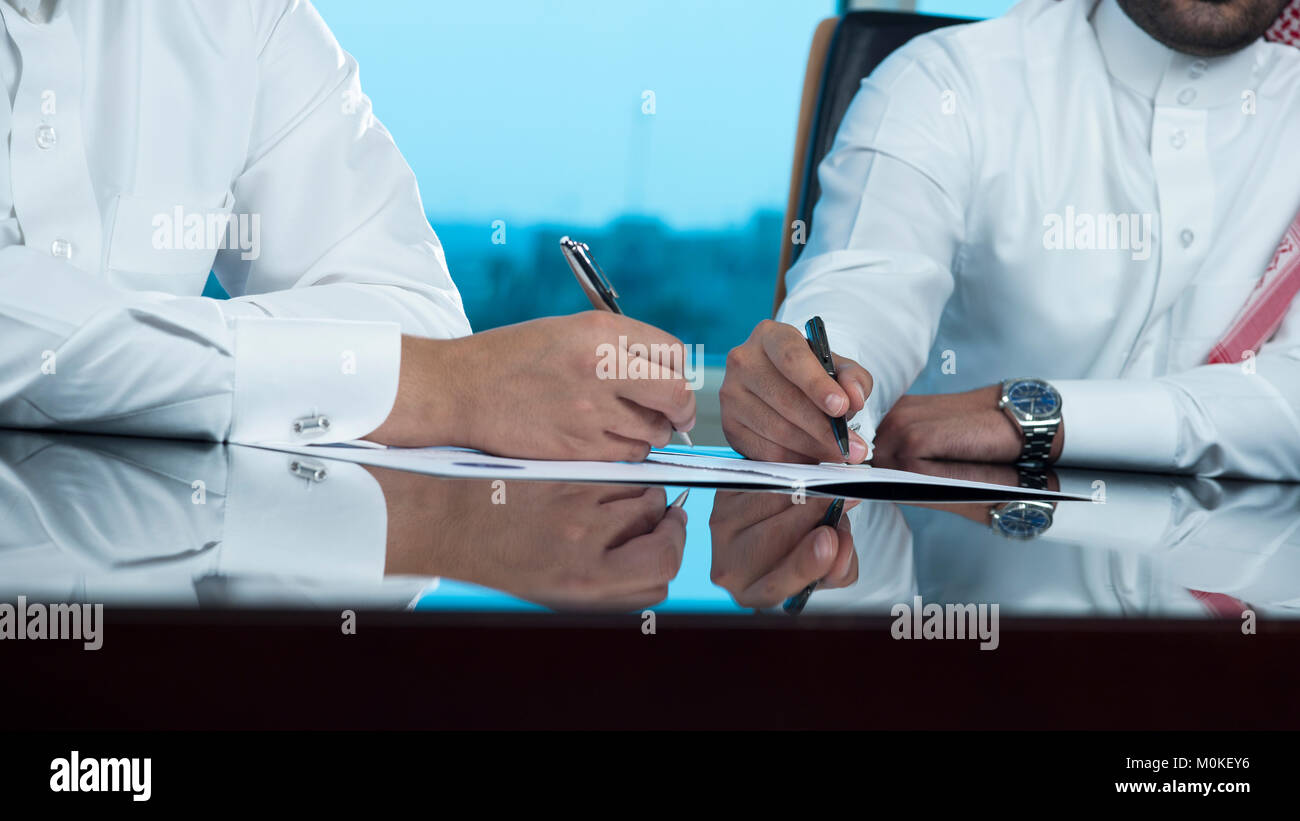 Due uomini di affari saudita Mani di firmare un documento, contratto o facendo una trattativa Foto Stock