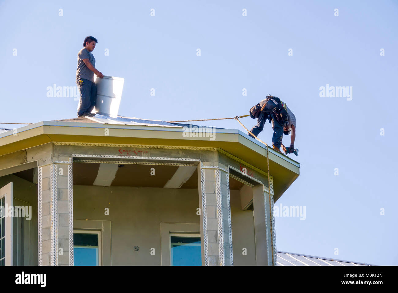 I lavoratori di installare un tetto di metallo sulla cima di una nuova costruzione condominio Foto Stock
