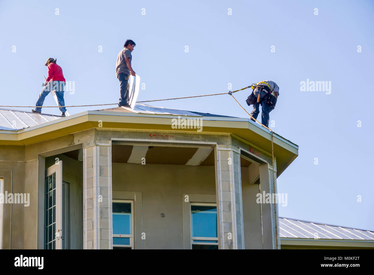 I lavoratori di installare un tetto di metallo sulla cima di una nuova costruzione condominio Foto Stock