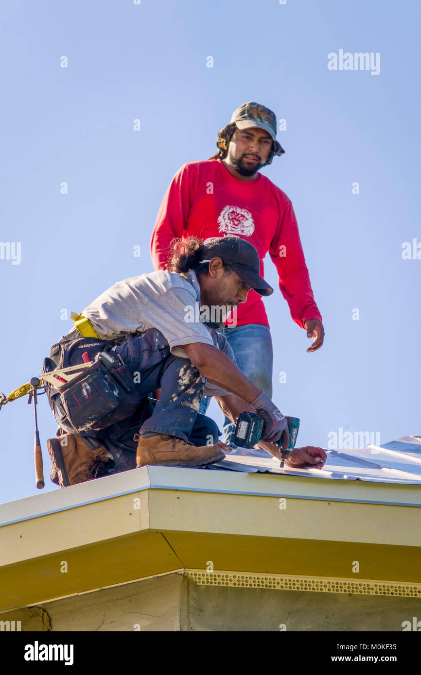 I lavoratori di installare un tetto di metallo sulla cima di una nuova costruzione condominio Foto Stock