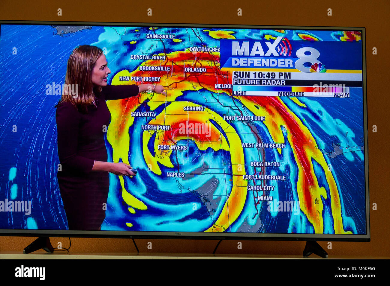 A seguito di un uragano Irma di avvertimento sulla televisione e un cellulare tenuto in mano lo smartphone dispositivo Foto Stock