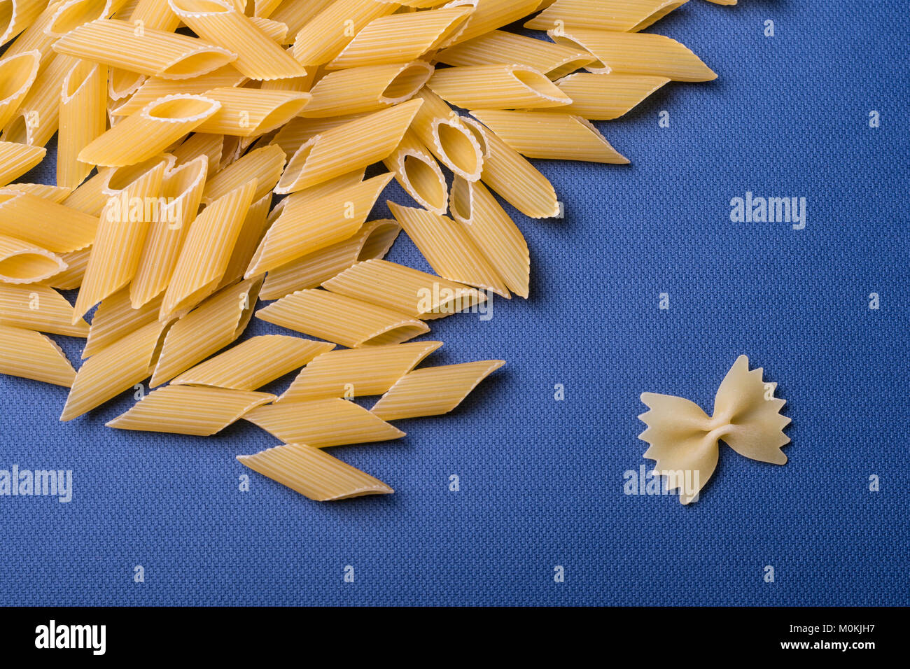 Tubolare di penne e singole farfalle di pasta su carta blu. Food texture di  sfondo, vista dall'alto Foto stock - Alamy