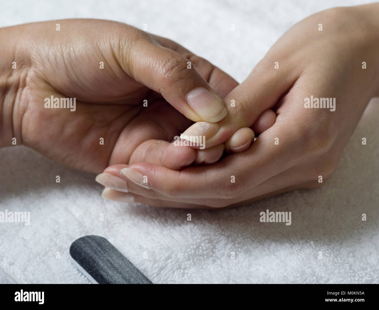 Una chiusura delle mani femminili facendo manicure, applicare la colla per unghie acriliche Foto Stock