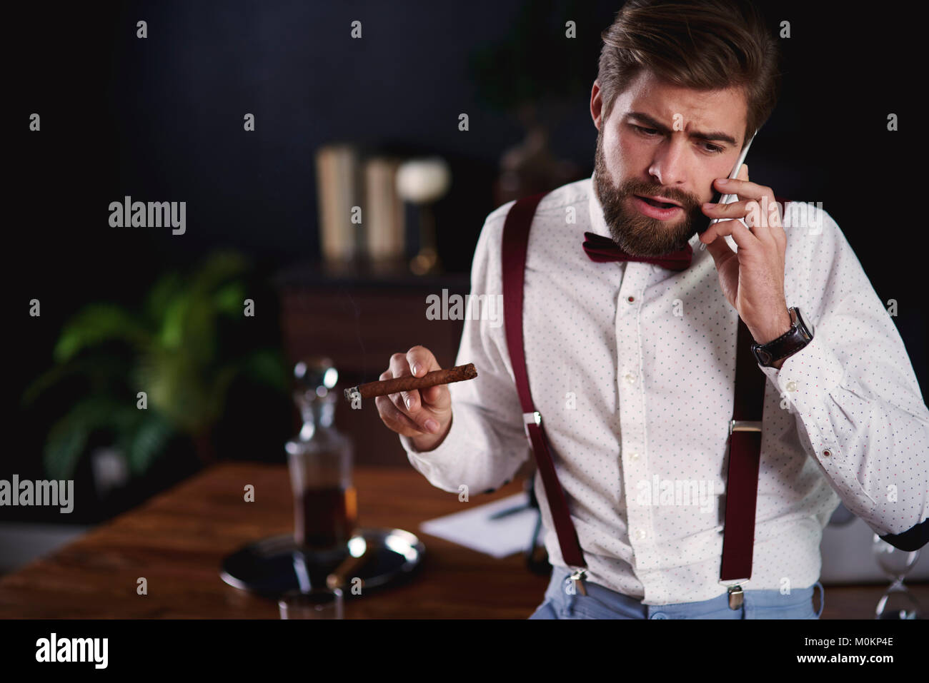 Imprenditore di fumare sigari cubani mentre la chiamata di business Foto Stock