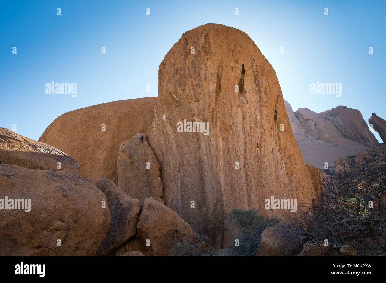 Un alpinista solitario è a malapena distinguibili tra le grandi formazioni rocciose di Spitzkoppe Foto Stock