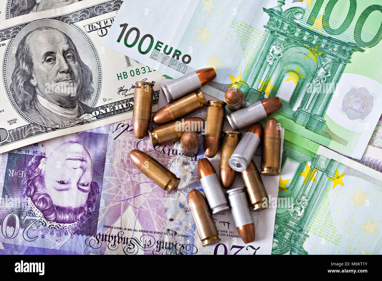 Denaro criminale, pochi proiettili sul denaro dollari, sterline, euro, il contesto finanziario Foto Stock